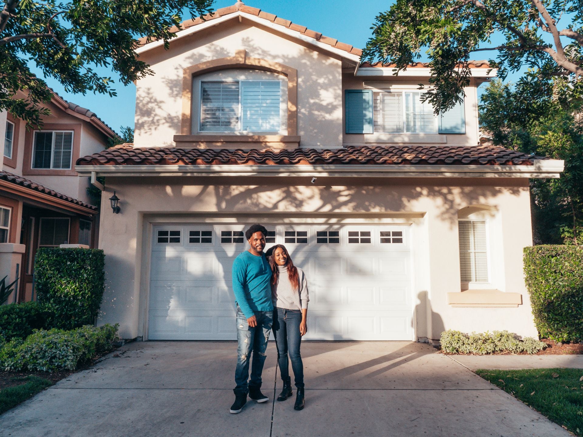Smiling couple in front of their home and garage