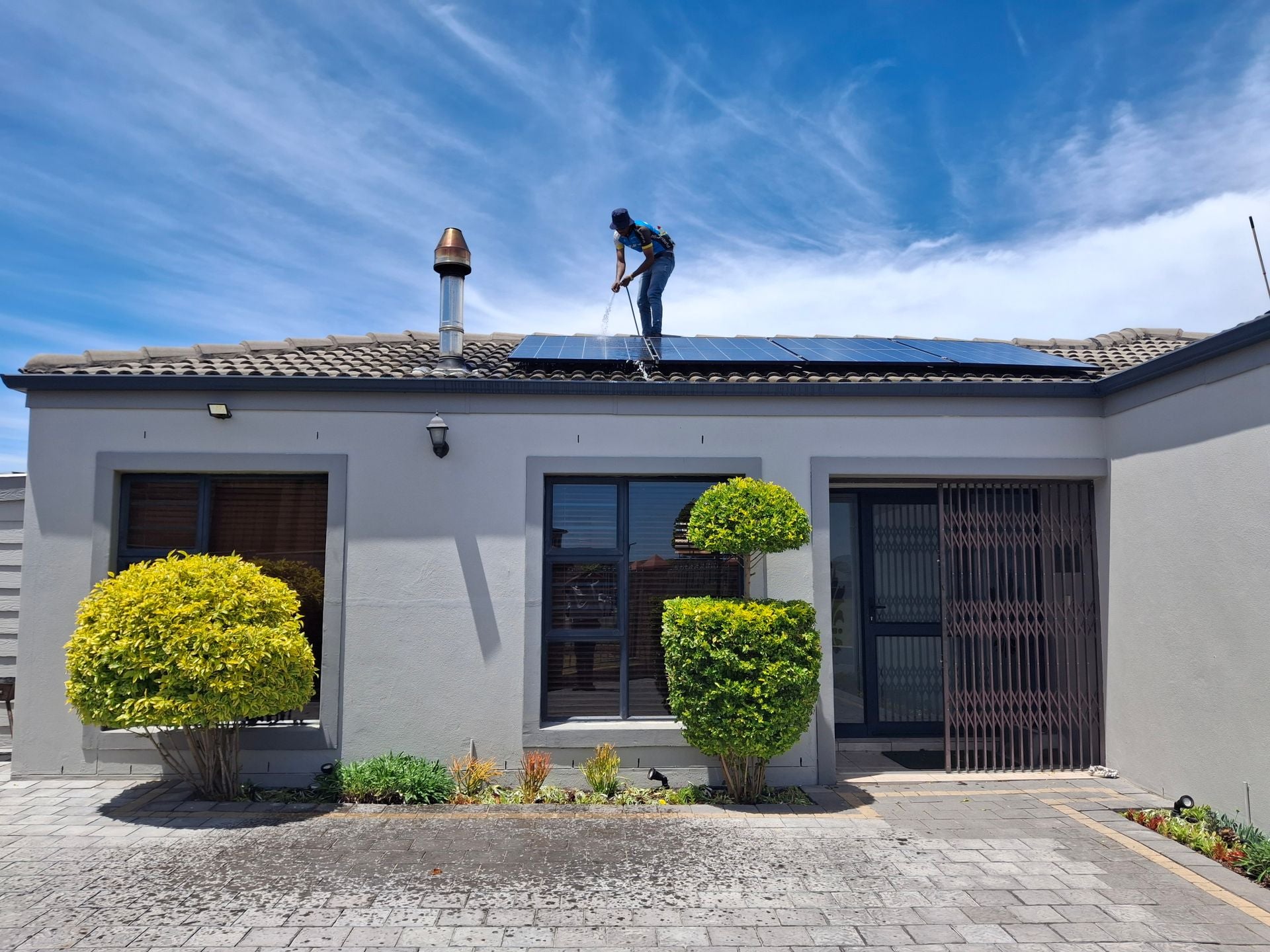 Technician servicing rooftop solar panels on a residential home